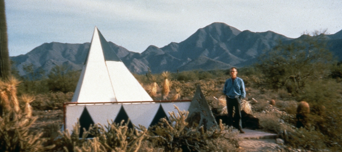David Dodge in the Sonoran desert standing next to his the triangular tent.